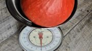 1 kg schwerer orangeroter Hokkaidokürbis auf einer Küchenwaage